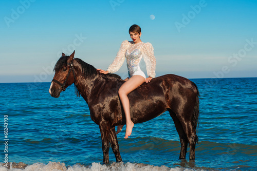 Young beautiful girl with a horse on the beach