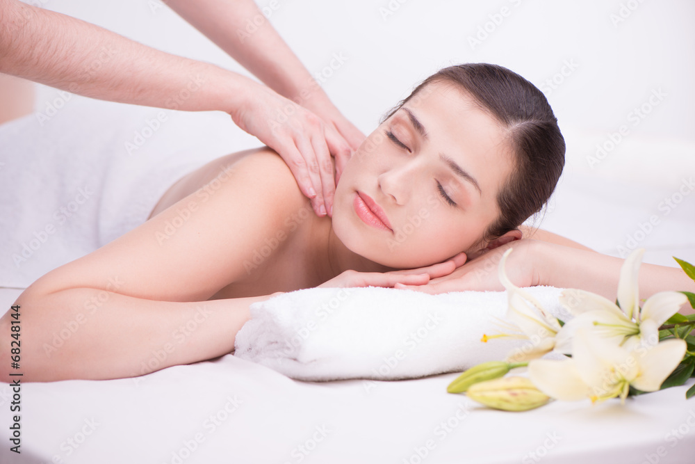 Relaxed woman with flowers in spa center enjoying massage Relaxed woman with flowers in spa center enjoying massage