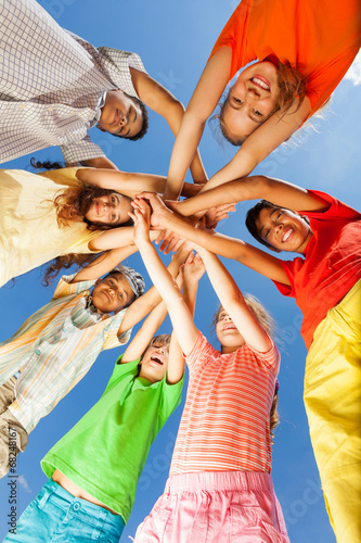 Kids put arms in star shape on sky background