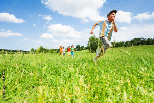 Excited boy runs away from his mates in field