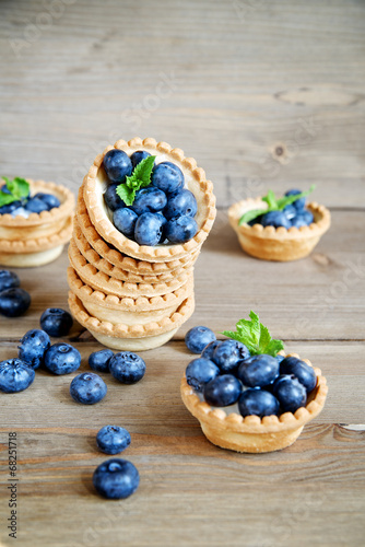 Tarts with blueberries on a wooden background