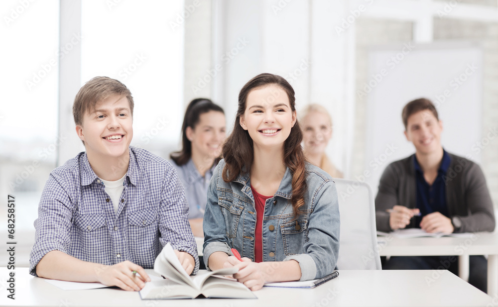 two teenagers with notebooks and book at school two teenagers with notebooks and book at school