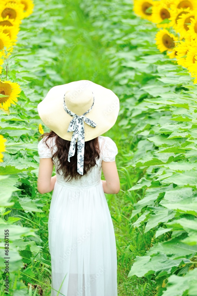 ひまわり畑に立っている白いワンピースと麦わら帽子を着ているアジア人の美しい女性 Stock Foto Adobe Stock