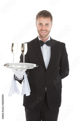 Confident Waiter Carrying Champagne Flutes On Tray