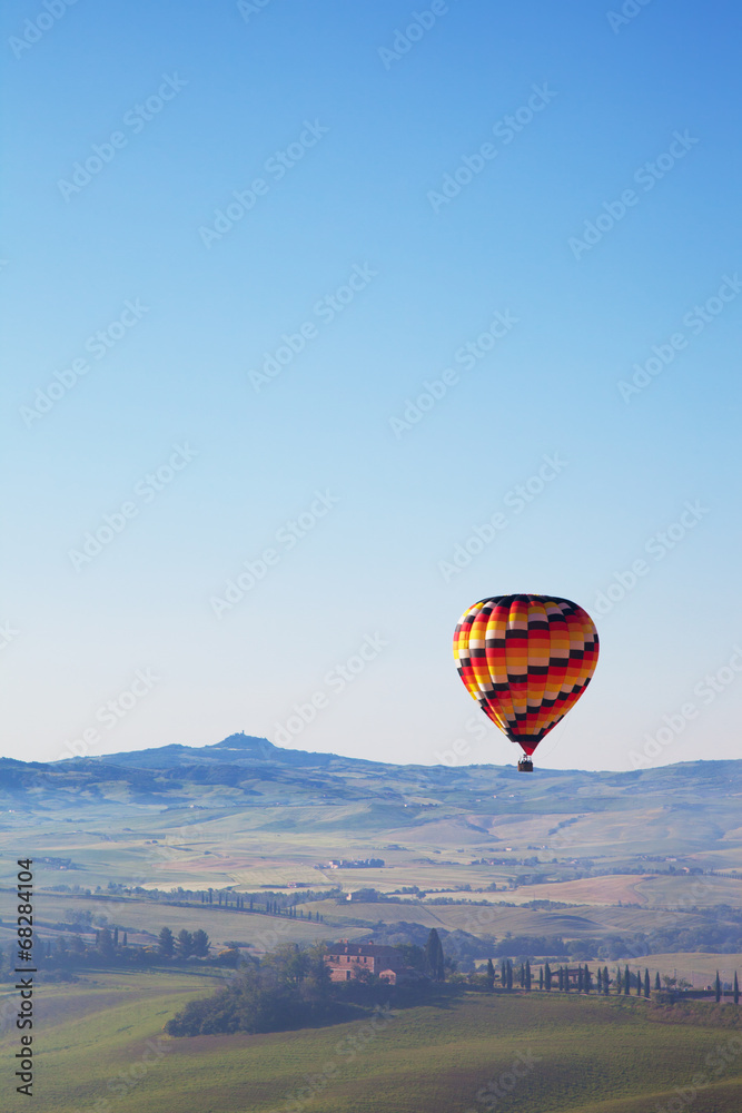 big balloon flies over rural houses, Tuscany, Italy