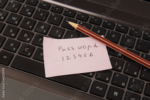 Sticky note with password and pencil on black laptop