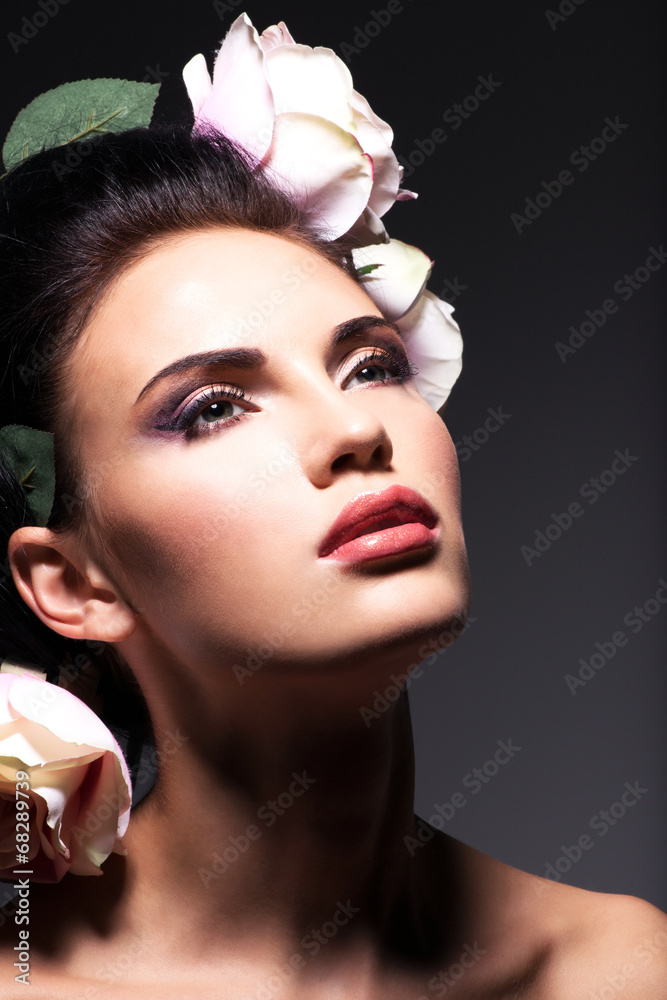 Naklejka premium Closeup portrait of beautiful young woman with pink flowers in h