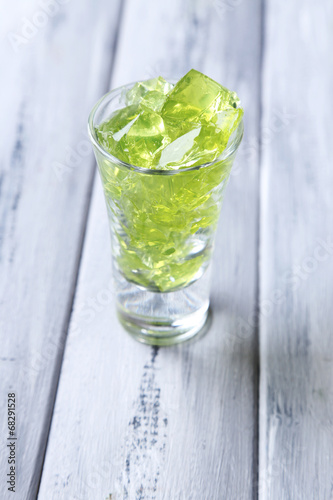 Green jelly with mint leaves in glass on wooden background