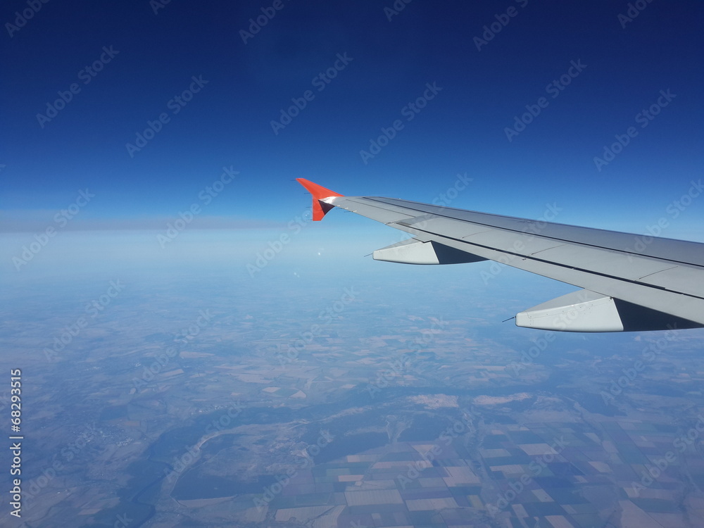 Obraz premium Wing of plane, ground and sky