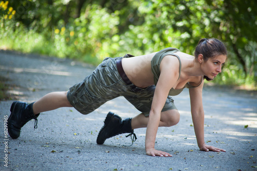 Beautiful military woman training push-ups in park