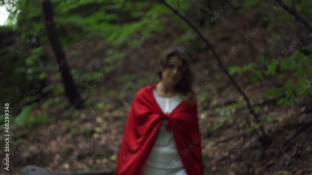 Mysterious woman in red cape walking in forest, slow motion Mysterious woman in red cape walking in forest, slow motion