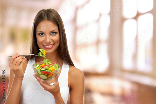 Beautiful young woman with salad on interior background