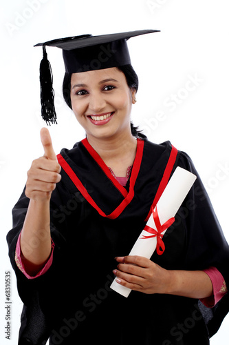 Smiling young graduation student making thumbsup gesture