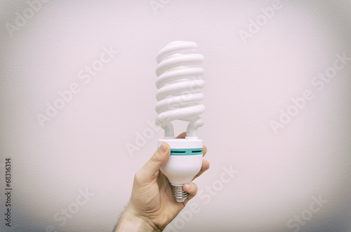 Hand holding big energy efficient fluorescent lamp.