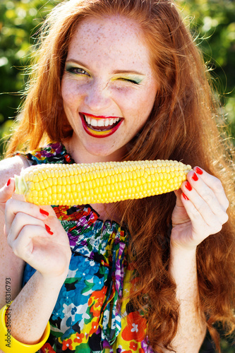 Smiling girl with freckles holding corn cob