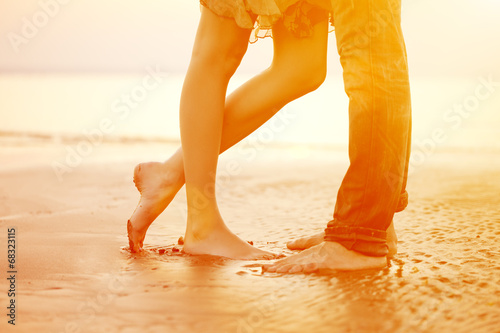 A loving young couple hugging and kissing on the beach at sunset