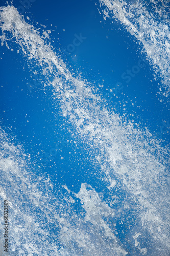 Fountain drops of pure brilliant water against a blue clear sky