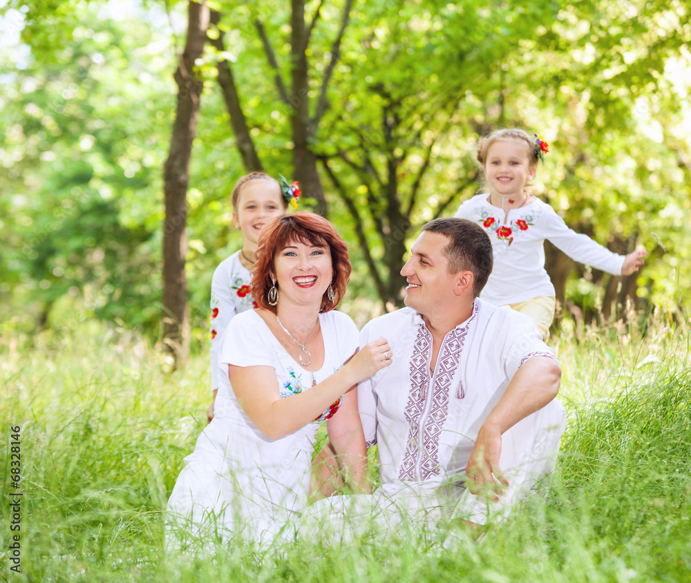 Young couple with little daughters in the summer park