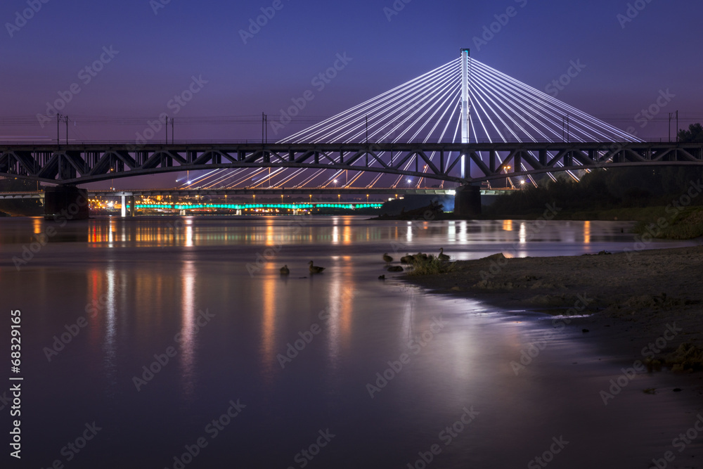 Backlit bridge at night and reflected in the water