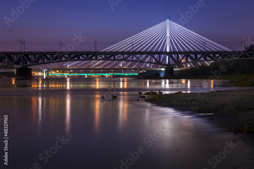 Backlit bridge at night and reflected in the water