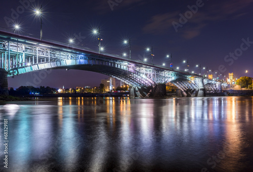 Fototapeta Naklejka Na Ścianę i Meble -  Backlit bridge at night and reflected in the water.