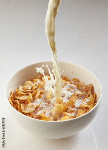 milk pouring into bowl with corn flakes