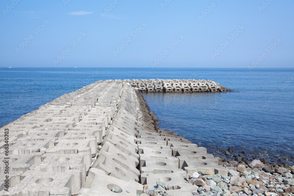 Breakwater concrete dam with blue sea and sky background
