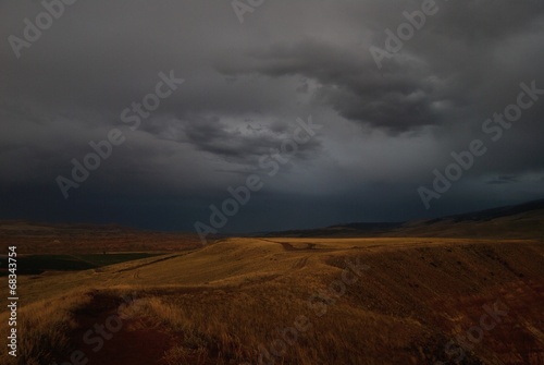 landscape of road between fields in thunderstorm