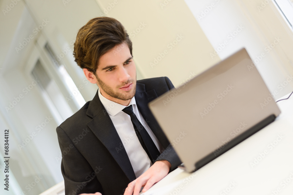 Businessman sitting at his laptop and working in his office Businessman sitting at his laptop and working in his office