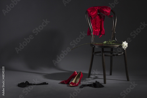 Sexy lingerie, shoes and a white rose on a retro chair.