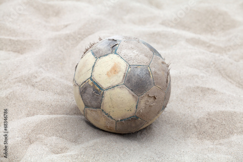 Old soccer ball on sand beach