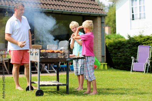Father and kids making barbecue at the backyard of the house