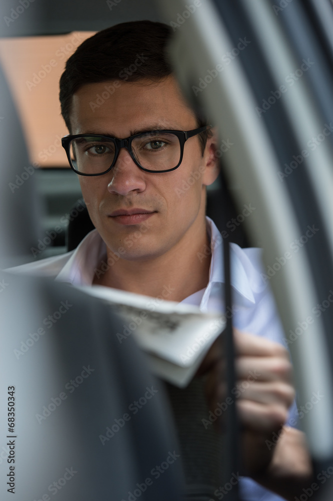 Businessman reading newspaper car