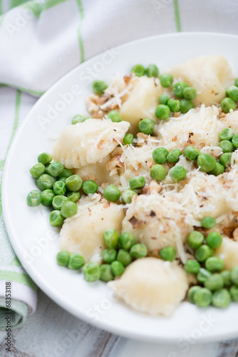 Close-up of ravioli with green peas, nuts and parmesan
