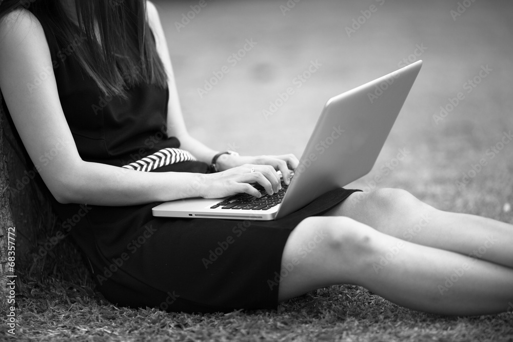Naklejka premium Beautiful young woman using laptop in park