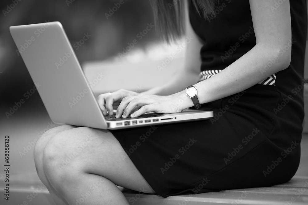 Naklejka premium Beautiful young woman using laptop in park