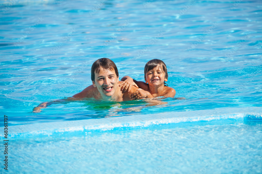 Smiling man with boy in swimming pool