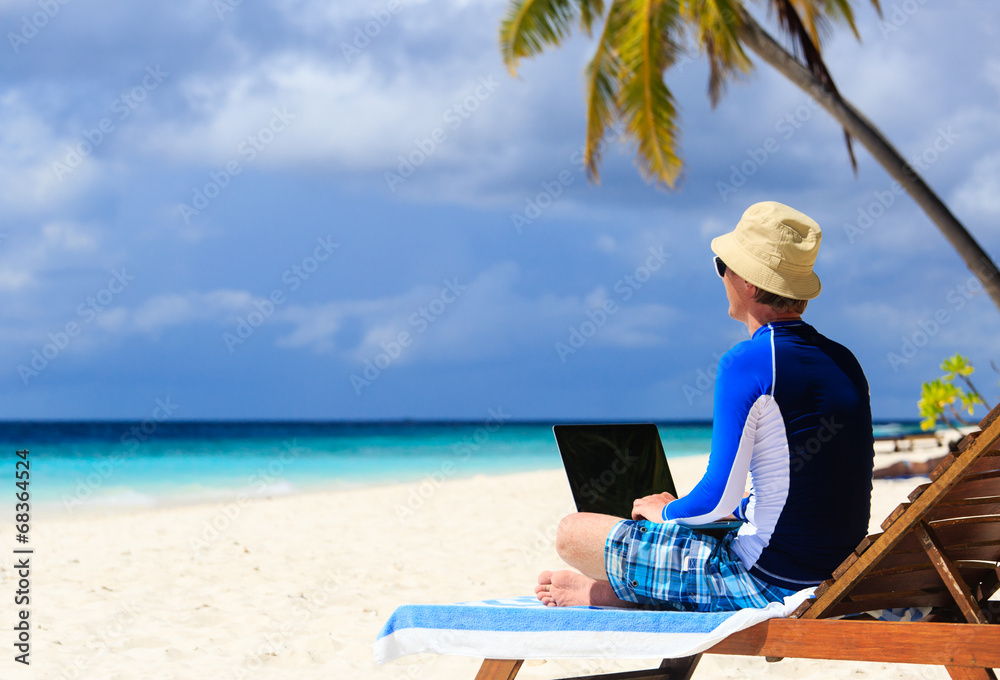 man with laptop on tropical vacation