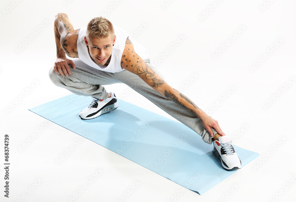 Fototapeta premium Ćwiczenia gimnastyczne na macie, mężczyzna ćwiczy jogę