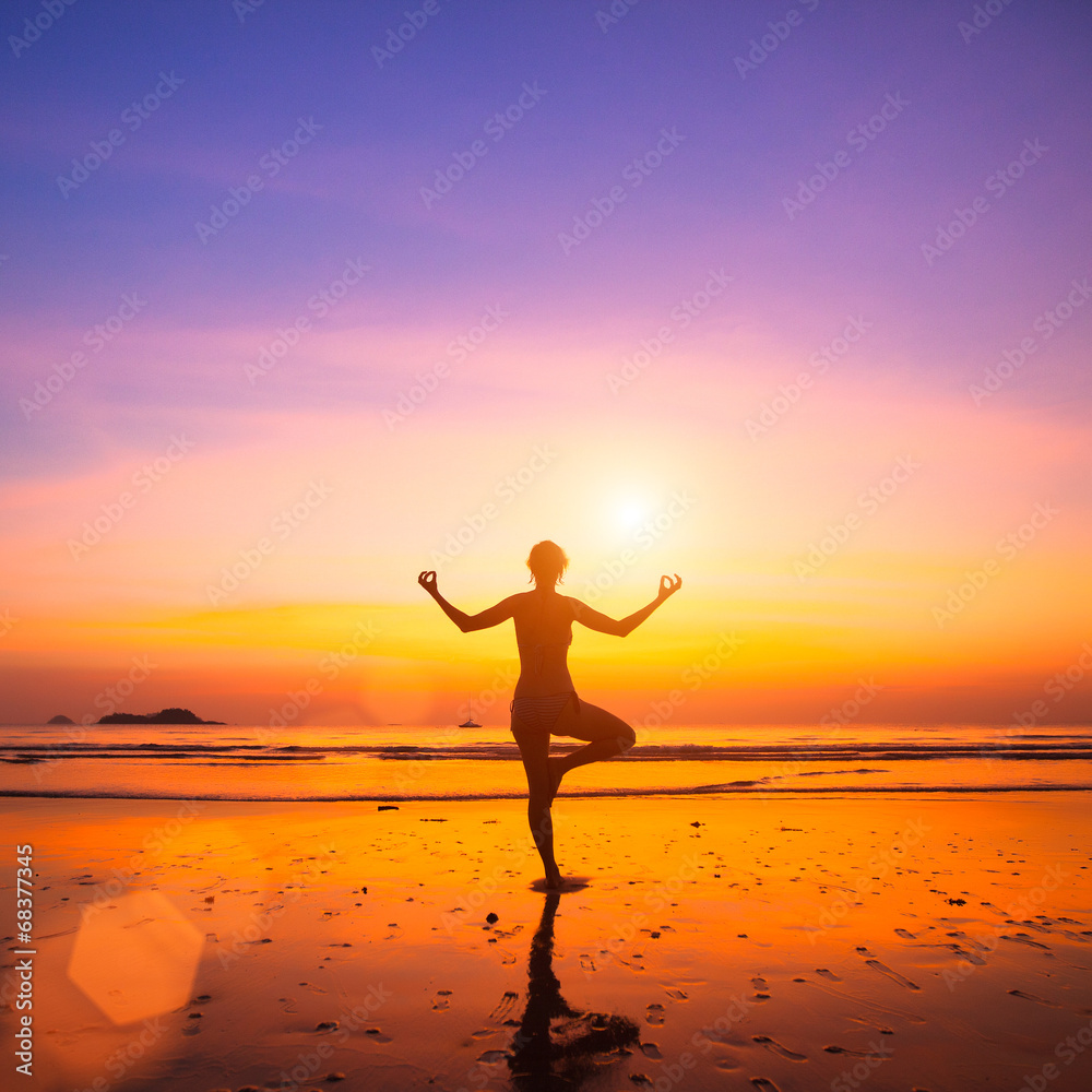 Yoga woman on sea coast at sunset.