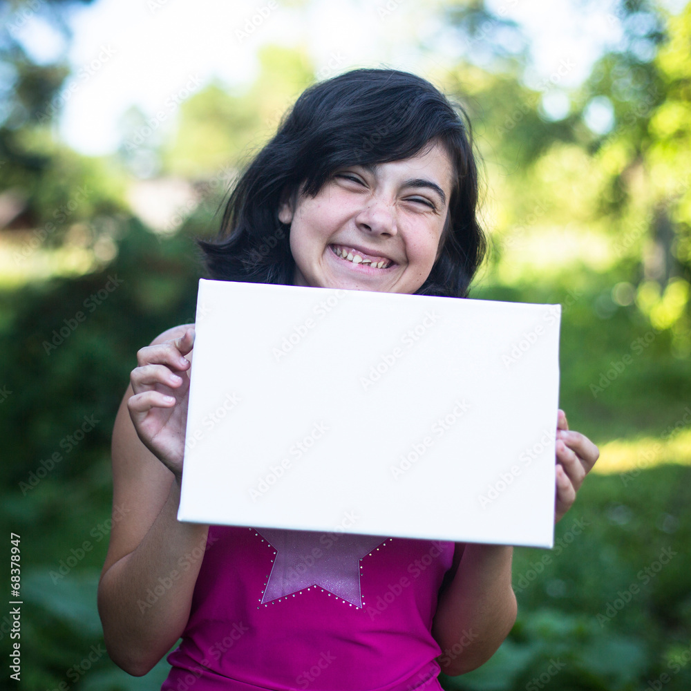 Fun girl holding clean white sheet paper, outdoors Fun girl holding clean white sheet paper, outdoors