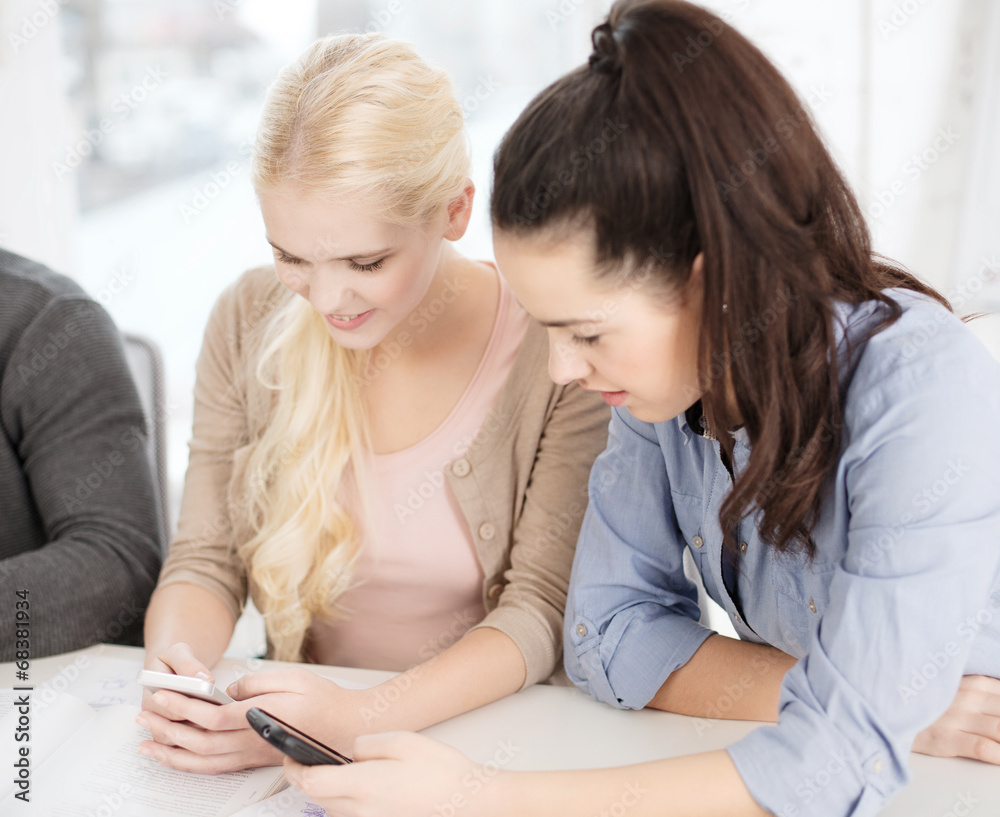 two teens with smartphones at school two teens with smartphones at school