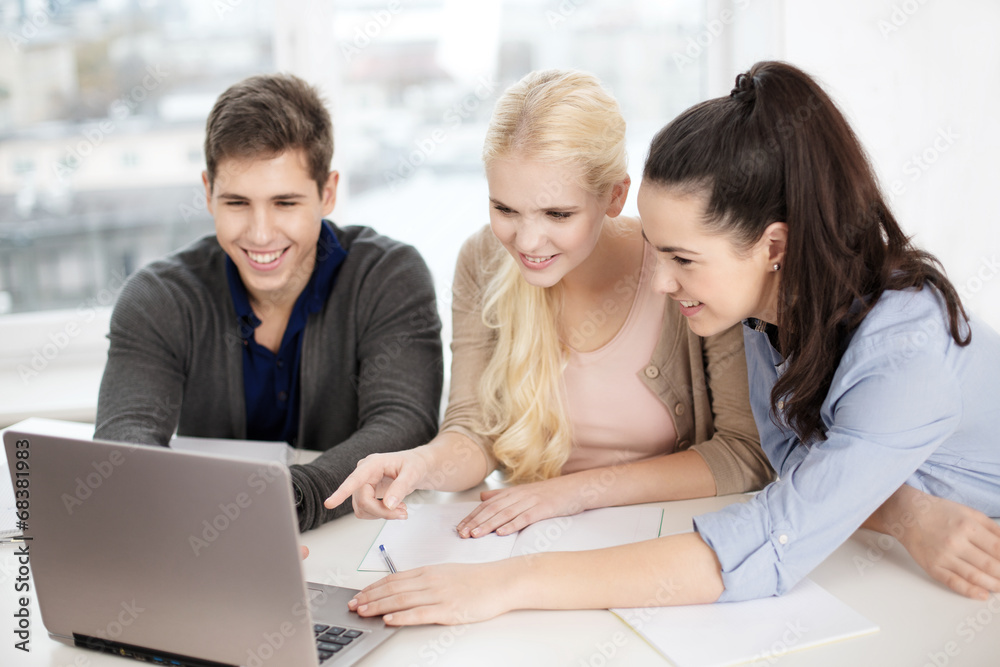 three smiling students with laptop and notebooks three smiling students with laptop and notebooks