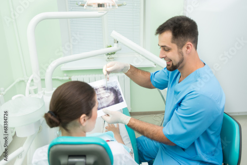 Smiling dentist with his patient explaining something
