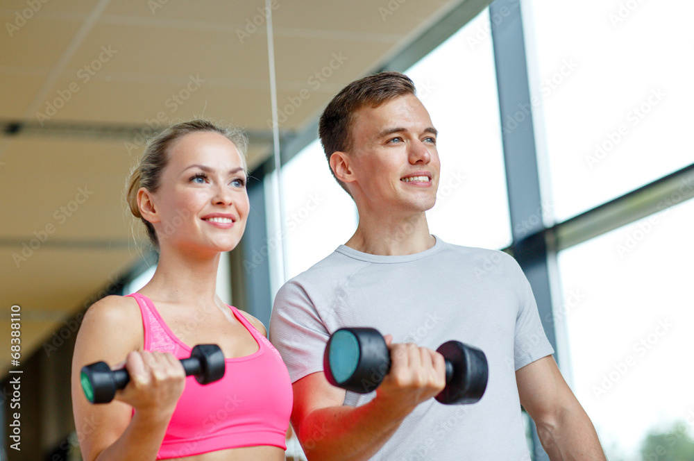smiling young woman with personal trainer in gym smiling young woman with personal trainer in gym