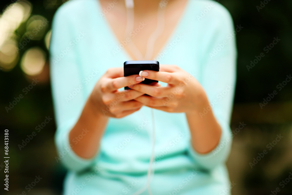 Closeup portrait of a woman using smartphone with headphones