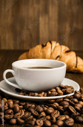 cup of coffee with coffee beans and croissant