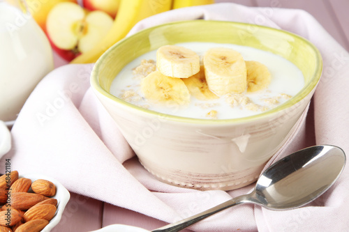 Tasty oatmeal with bananas and milk on table close up