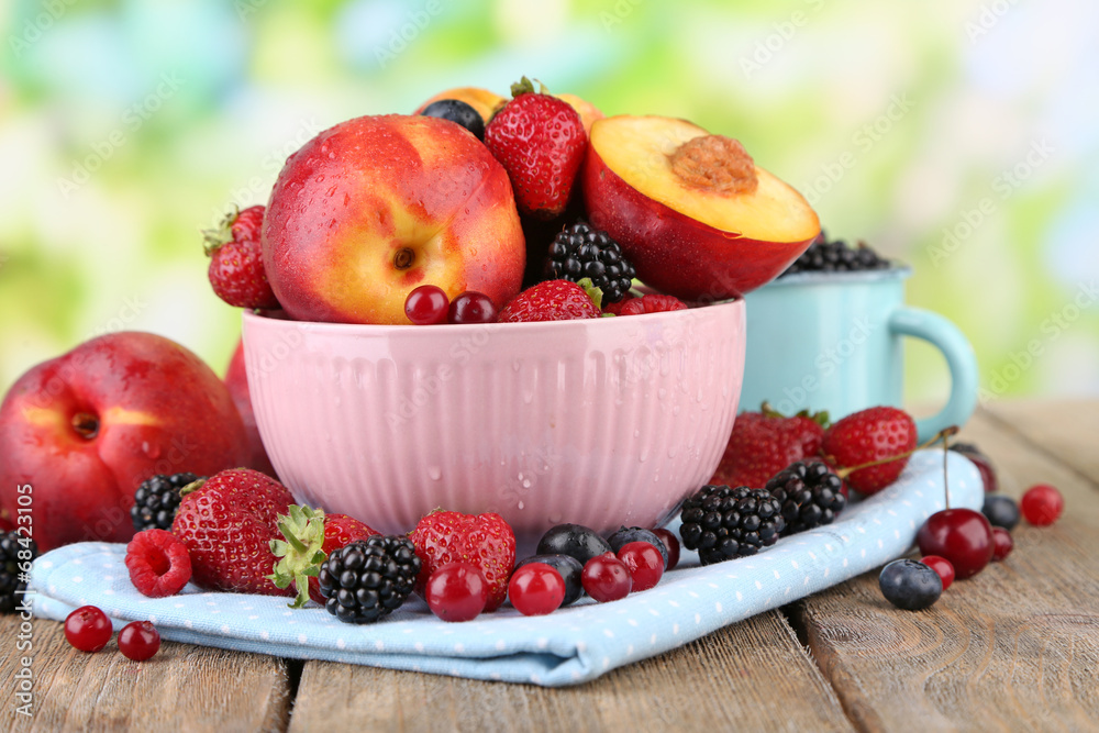 Peaches and berries in bowl on table on natural background Peaches and berries in bowl on table on natural background