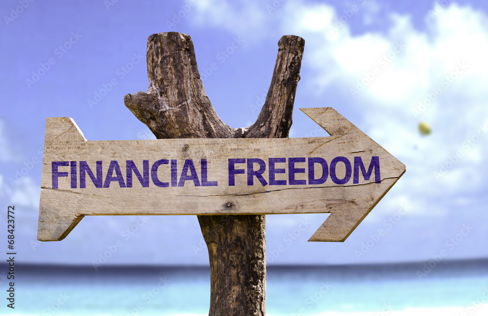Financial Freedom wooden sign with a beach on background